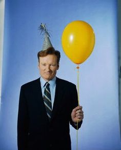 a man in a suit and tie holding a yellow balloon