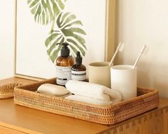 a wooden table topped with a basket filled with bottles and containers next to a plant