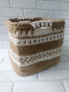 a brown and white knitted basket sitting on top of a brick wall next to a window