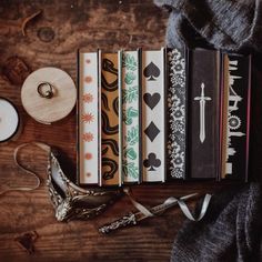 a wooden table topped with lots of books next to a candle and some other items