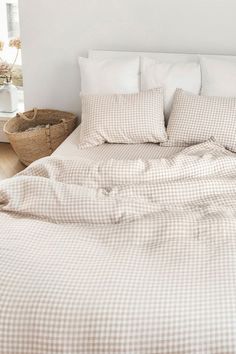 an unmade bed in a white bedroom with checkered sheets and pillowcases