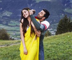 a man holding a woman on top of a lush green hillside