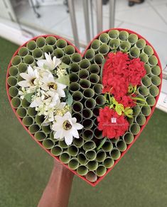 a heart shaped vase with flowers in it