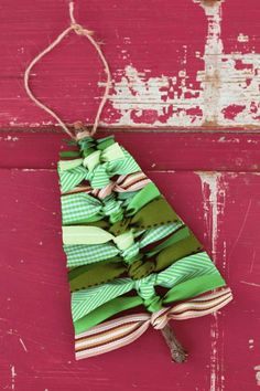 a christmas tree ornament hanging on a red door with green and white ribbons