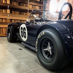 an old fashioned race car is parked in a garage with brick walls and flooring