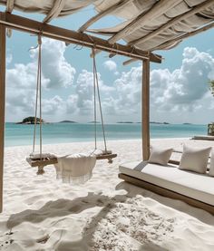 a swing bed on the beach in front of an open air area with white sand and blue water