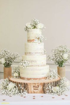 a wedding cake sitting on top of a wooden table next to white flowers and baby's breath