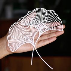 a hand holding a white paper fan in it's palm