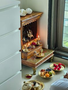 a person sitting on the floor in front of a small shrine