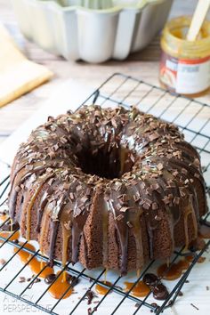 a chocolate bundt cake sitting on top of a cooling rack with caramel sauce