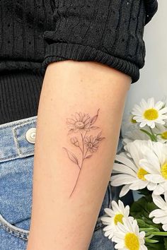 a woman's arm with daisies on it and a small flower in the middle