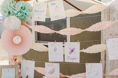 there are many cards hanging on the wall with paper flowers and umbrellas attached to it