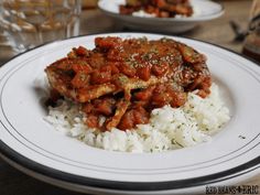 a white plate topped with rice and meat covered in sauce