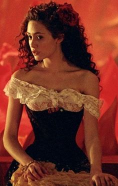 a woman in a corset sitting on a chair with her hand over her shoulder