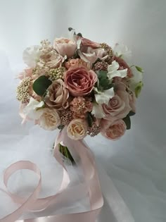 a bridal bouquet with pink ribbon and flowers on white fabric, ready to be used as a bride's bouquet