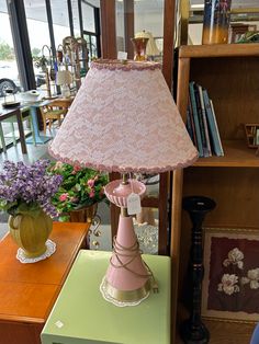 a pink lamp sitting on top of a green table next to a vase filled with flowers