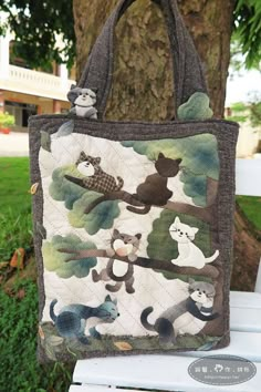 a handbag with cats and dogs on it sitting on a bench in front of a tree