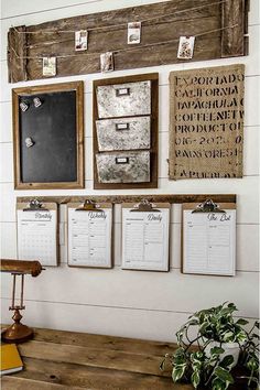 a wooden table topped with clipboards next to a wall mounted chalkboard and calendars