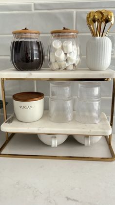 three tiered shelf with glass jars and bowls on it, one is gold and the other is white