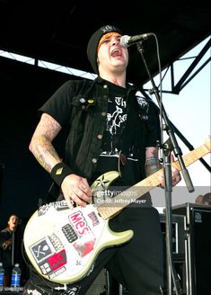 a man singing into a microphone while playing an electric guitar at a music festival stock photo