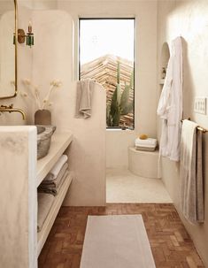 a bathroom with white walls and wooden flooring next to a bathtub filled with towels