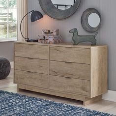 a wooden dresser sitting next to a window with a mirror on it's side