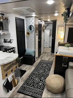 a living room and kitchen area in a small space with white walls, wood flooring and black accents