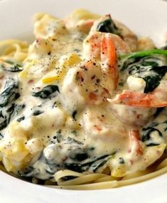 pasta with shrimp, spinach and cheese sauce in a white bowl on a table