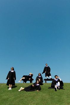 four people in graduation gowns are sitting on a bench and posing for the camera