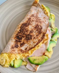 an omelet on a plate with avocado and meat in the middle