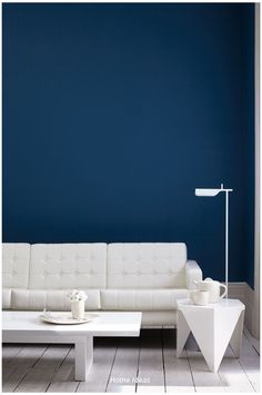 a white couch and table in a room with blue walls, hardwood floors and flooring