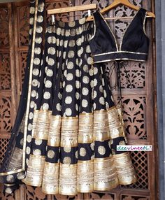 Made to Order/Measurement/Custom Order Lehenga - Color : Black - Fabric : Brocade Silk with Embroidered Border - Fully flared kalidaar lehenga with rich lining - Princess Cut Padded Sleeveless Raw Silk Blouse - Black Embellished Net Dupatta with Gold and Brocade Border - Drawstring closure with Tassels Fabric Care : Dry Clean Only Disclaimer: Please note the photographs are taken by mobile camera in sunlight The actual color of the product might slightly differ due to exposure of light or monito Black Raw Silk Traditional Wear For Party, Black Chanderi Lehenga With Traditional Drape, Black Chanderi Lehenga With Zari Work, Black Brocade Dupatta For Wedding, Festive Black Chanderi Lehenga, Black Bollywood Lehenga In Raw Silk, Black Bollywood Raw Silk Lehenga, Black Art Silk Traditional Wear For Reception, Black Bollywood Style Raw Silk Lehenga