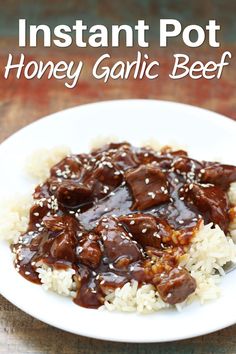 a white plate topped with beef and rice on top of a wooden table next to a fork