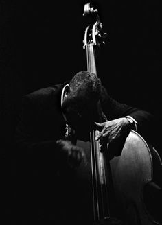 a black and white photo of a man playing the cello