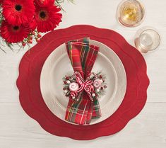 a place setting with red flowers and napkins