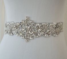 "This dazzling vintage inspired bridal sash is embellished with high quality glass crystals and pearls. Sparkles beautifully. Elegant and lovely design that sparkles beautifully. Very pretty in person. Embellishment Width: 3.5\" wide at the center and tapers to 1.5\" on the sides Embellishment Length: 13.5\" long Total Sash Length: sash is made with double faced satin ribbon 1.5\" wide and is 3 yards long. PROCESSING: Please allow 3-5 business days for production. Also be sure to leave the date Beaded Bridal Sash, Gold Sash, Bridal Sash Belt, Bridal Applique, Wedding Dress Sash, Wedding Belt, Crystal Belt, Wedding Sash Belt, Deal Kent