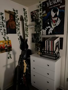 there is a guitar and various records on the shelf in this room with plants growing up against the wall