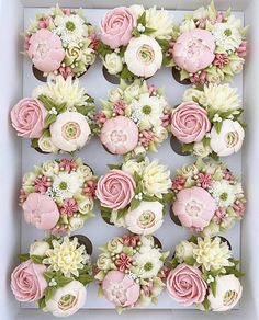 cupcakes decorated with pink and white flowers in a box