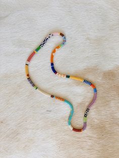 a multicolored beaded necklace laying on top of a white fur covered floor