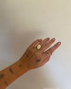 a woman's hand with tattoos on it and a gold ring in the middle