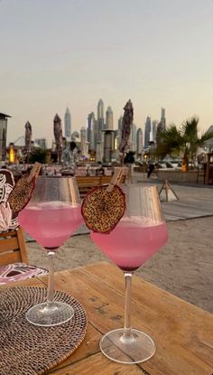 two glasses filled with pink liquid sitting on top of a wooden table next to each other