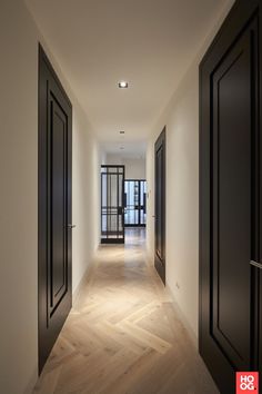 an empty hallway with black doors and wooden floors