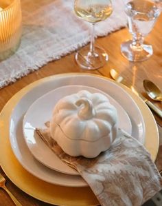 a white plate topped with a pumpkin on top of a wooden table next to silverware