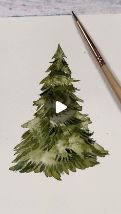 a watercolor painting of a green christmas tree on white paper next to a brush