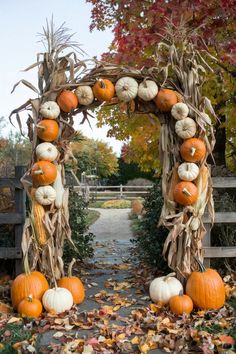 an archway decorated with pumpkins and corn stalks