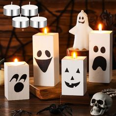 halloween candles with faces and ghost on them sitting in front of a wooden box filled with candles