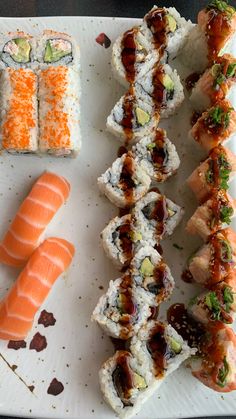 sushi is arranged on a white plate with carrots