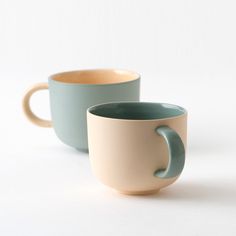 two coffee mugs sitting side by side on a white surface