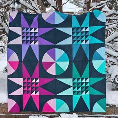 a quilt is hanging on a fence in the snow