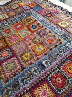 a multicolored crocheted blanket on top of a bed